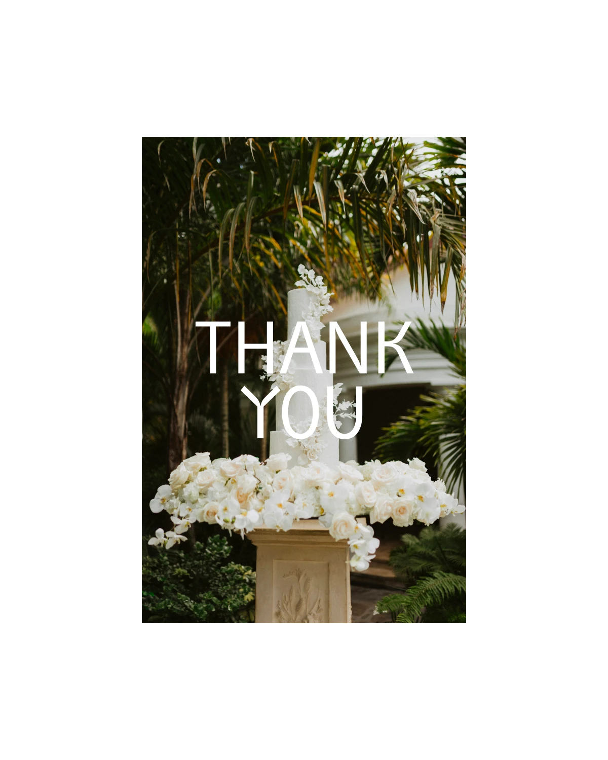 A tall white wedding cake with floral details on a pedestal, surrounded by palm trees. White „THANK YOU“ text overlay. A tall white wedding cake with floral details on a pedestal, surrounded by palm trees. White